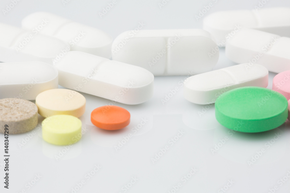 Pharmacy theme. Multicolored Isolated Pills and Capsules on the White Surface. Closeup Pharmacy theme. Multicolored Isolated Pills and Capsules on the White Surface. Closeup
