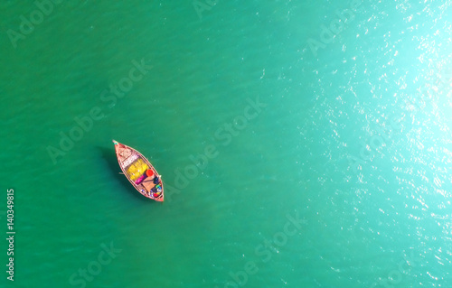 Fishing boat floating in the sea. The beautiful bright blue water in a clear day.Aerial view.Top view. © MAGNIFIER