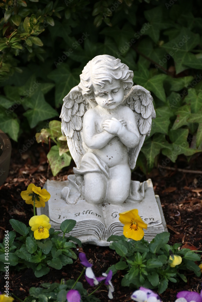 Engel trauert auf Grab mit Blumen im Frühling