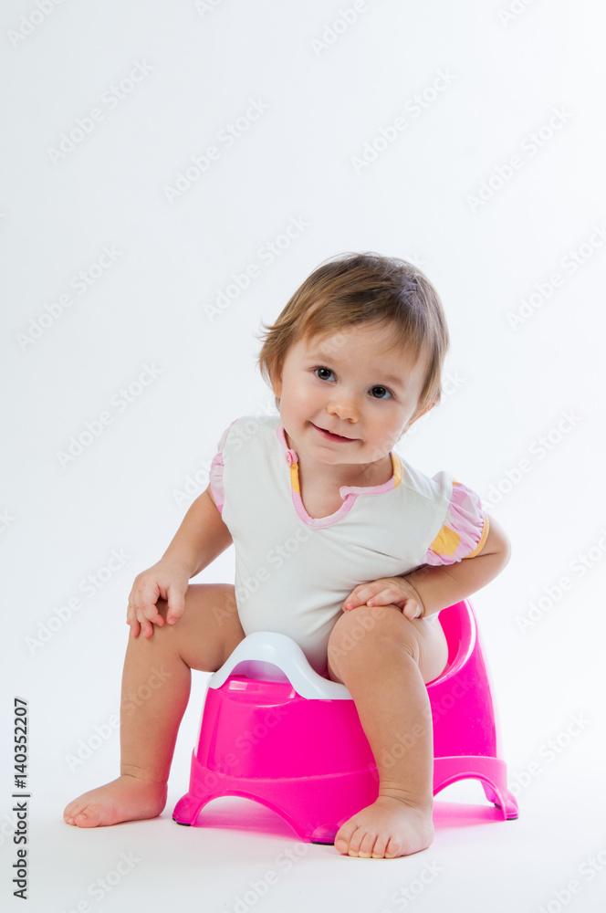 Little smiling girl sitting on a pot. Isolated on white background. Little smiling girl sitting on a pot. Isolated on white background.