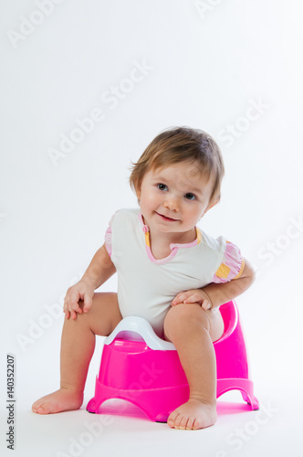 Little smiling girl sitting on a pot. Isolated on white background.