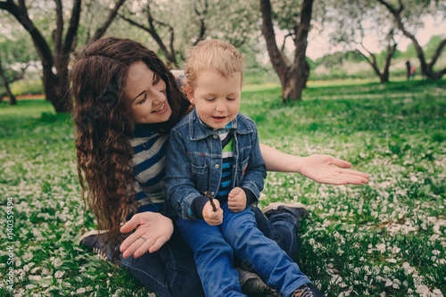 happy young mother and toddler son walking together outdoor and playing, candid lifestyle shot photo