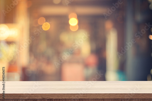 Empty wooden table for product placement or montage and blurred coffee shop backdrop.