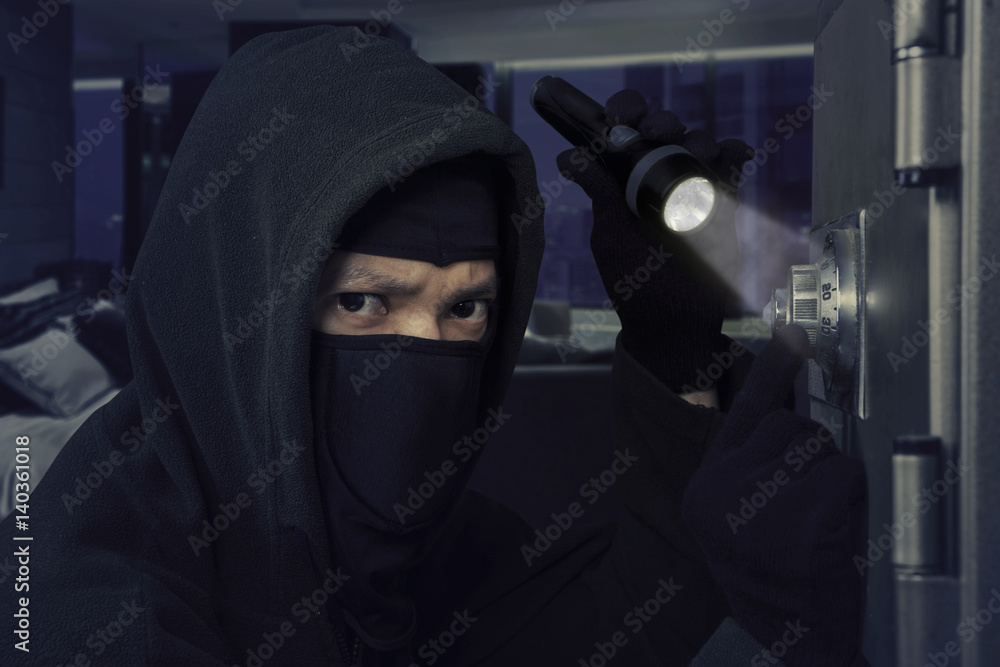Burglar with flashlight opens bank vault Burglar with flashlight opens bank vault