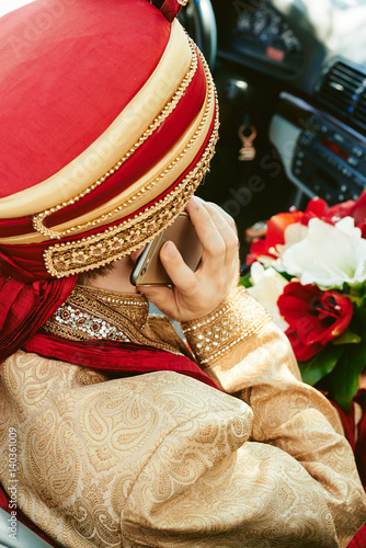 Indian groom speaking phone in car red headdress