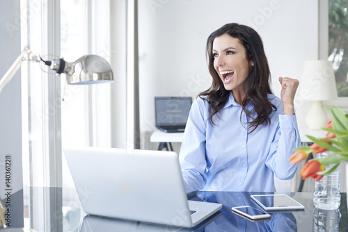 Success guaranteed. Shot of an overjoyed young businesswoman sitting at desk in front of laptop and celebrating the success.