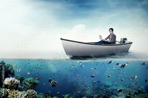 College student with laptop on boat © Creativa Images