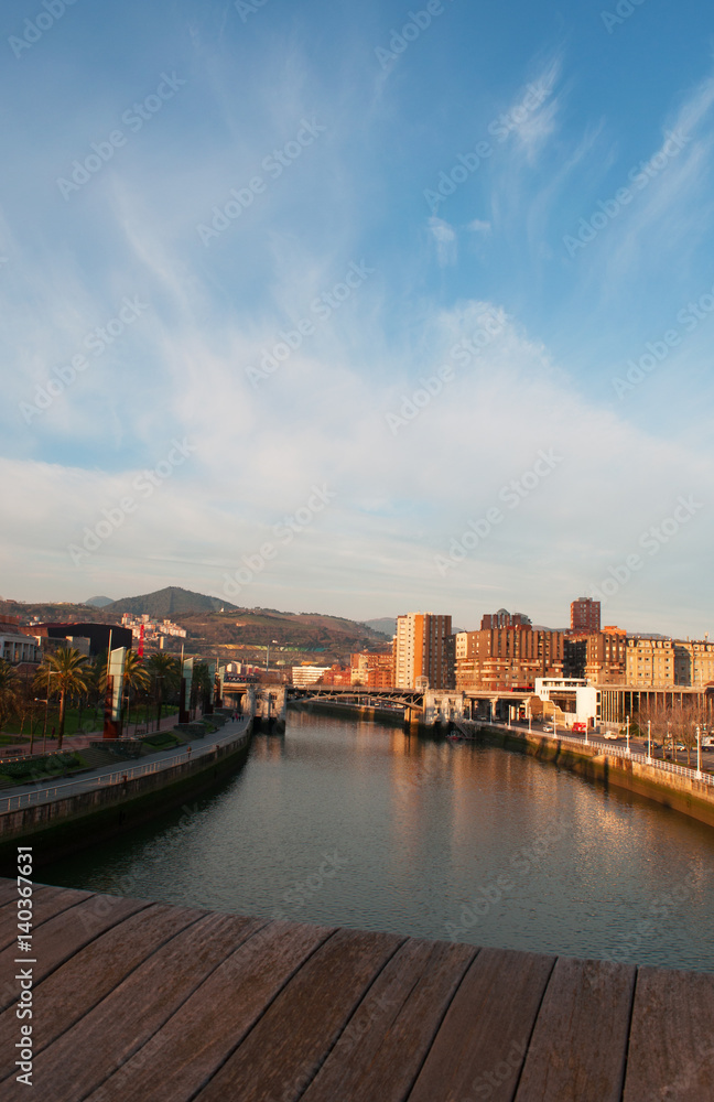 Spagna, 28/01/2017: lo skyline di Bilbao subito dopo l'alba visto dal ponte di legno Pedro Arrupe