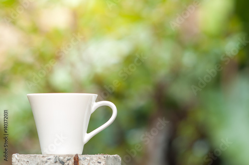 Coffee mug with blurry nature background.