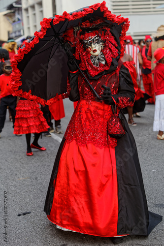 Touloulou en noir et rouge sous son parapluie à la journée des diables rouges du carnaval de Cayenne en Guyane française  © galaad973