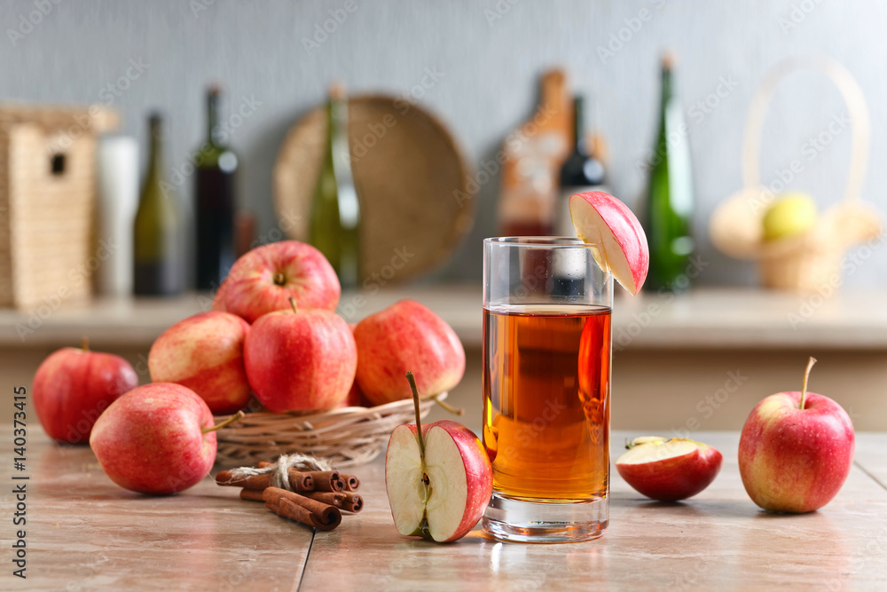 Glass of apple juice and ripe pink apples on a kitchen table Glass of apple juice and ripe pink apples on a kitchen table