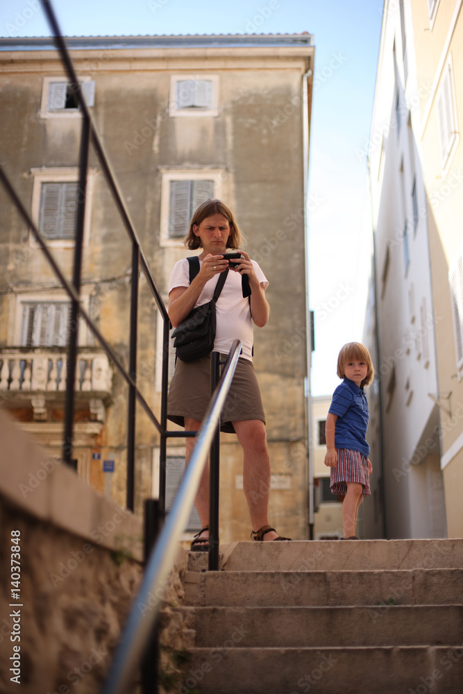 A man with a camera and a small son on the street of the old city. Zagreb, Croatia.
