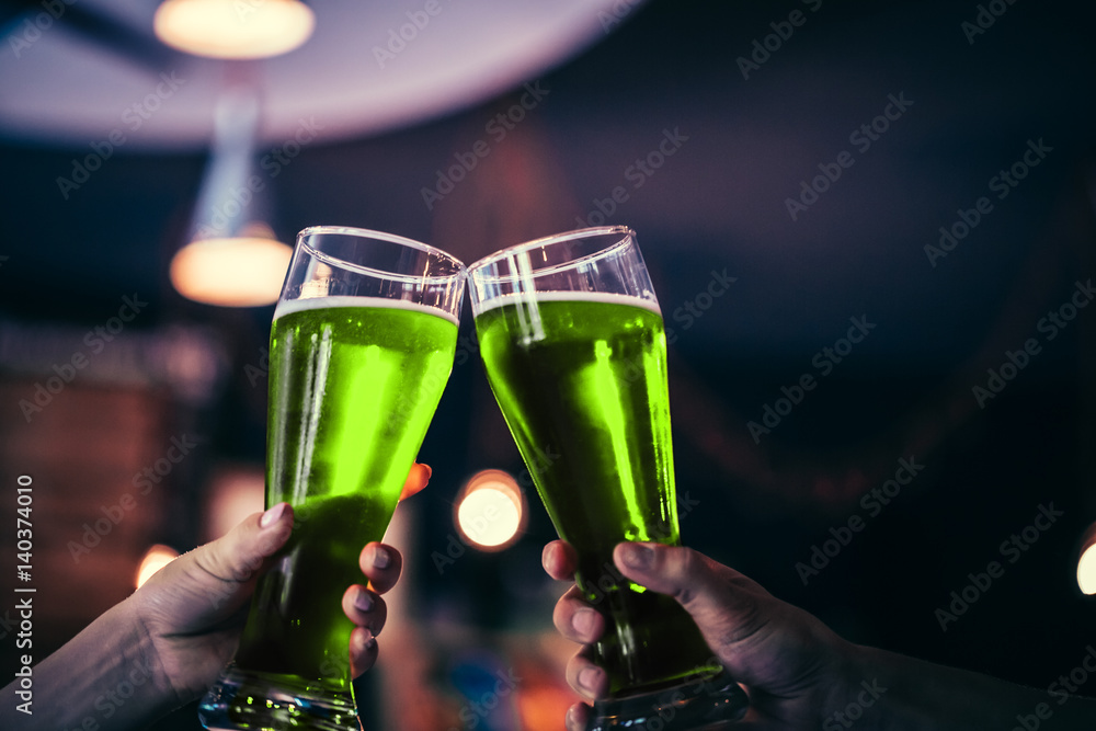 Φωτογραφία Two friends toasting with glasses of green beer at the pub with free space for your text