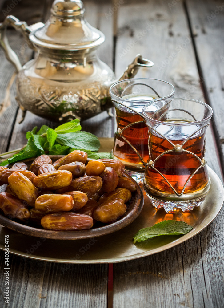 Tea with mint in arab style and dates on wooden table. Tea with mint in arab style and dates on wooden table.