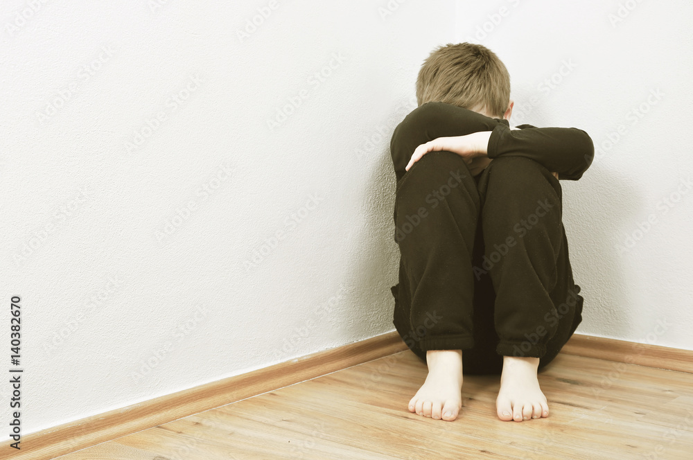 Small abused boy crying in the corner of his home because of domestic violence Small abused boy crying in the corner of his home because of domestic violence