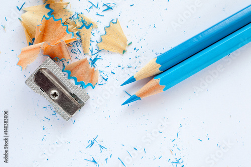 two blue wooden pencils, sharpener and blue pencil shavings on white photo