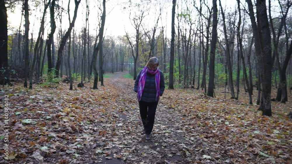 Senior woman with short hair and glasses on her eyes walking in autumn woods. Senior woman with short hair and glasses on her eyes walking in autumn woods.