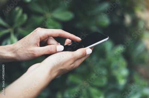 Female hands using smartphone isolated on background green nature wall mockup  hipster manager holding mobile gadget  person text message outside  connect content  close mock up