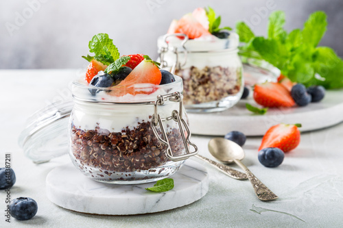 Gluten free breakfast with red quinoa, yogurt and berries in glass jar. Healthy super foods concept.