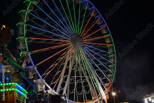 Colorful blurry lights of amusement park ferris wheel and rollercoaster on the night background