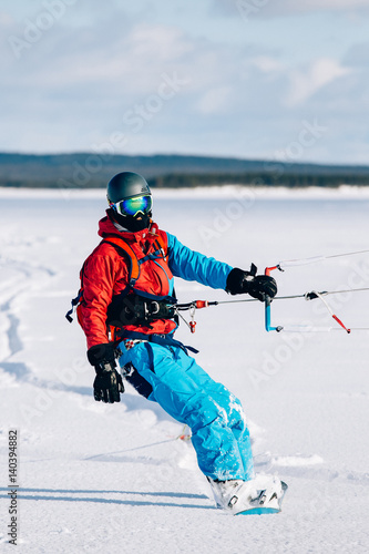 Snowkiting. Male athlete snowboarder rides a kite skiing on a frozen lake. The Kola Peninsula. kiting. Snowkite