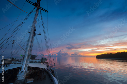 Indonesian Sunset from a Schooner Sailboat. Sailing through the Raja Ampat archipelago on a traditional phinisi schooner during a glorious sunset. 