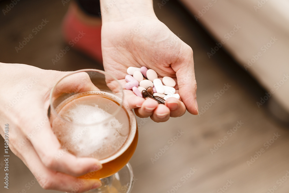 addict problem, woman with pills and beer in hands.