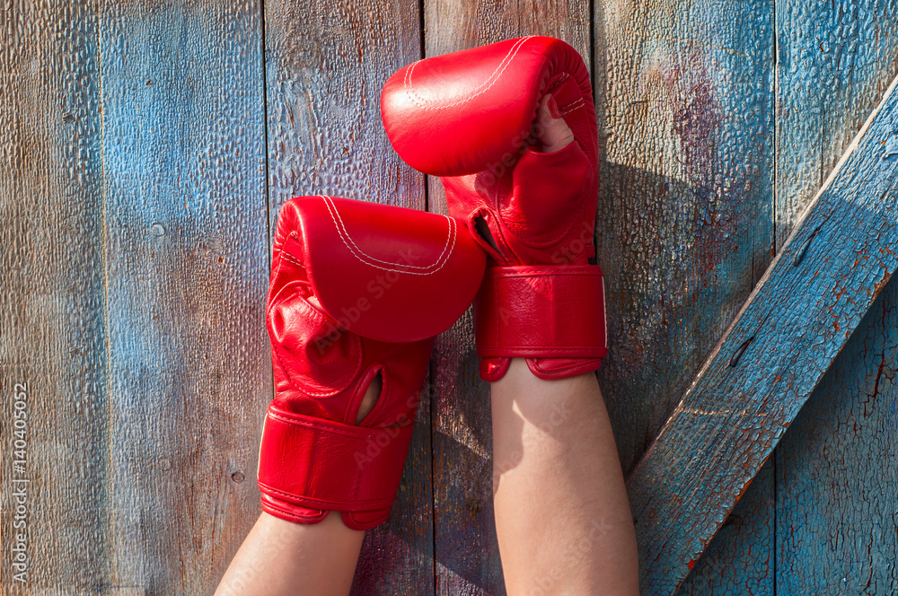 pair of female hands in red boxing gloves on a blue background