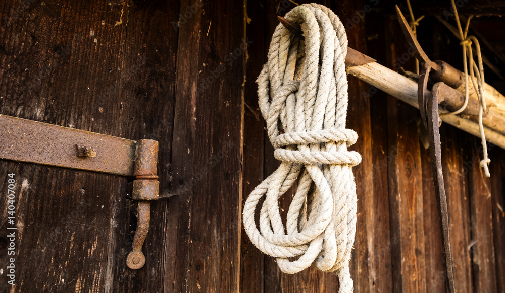 Seil hänt an einem Bootshaken an einer Holzwand.