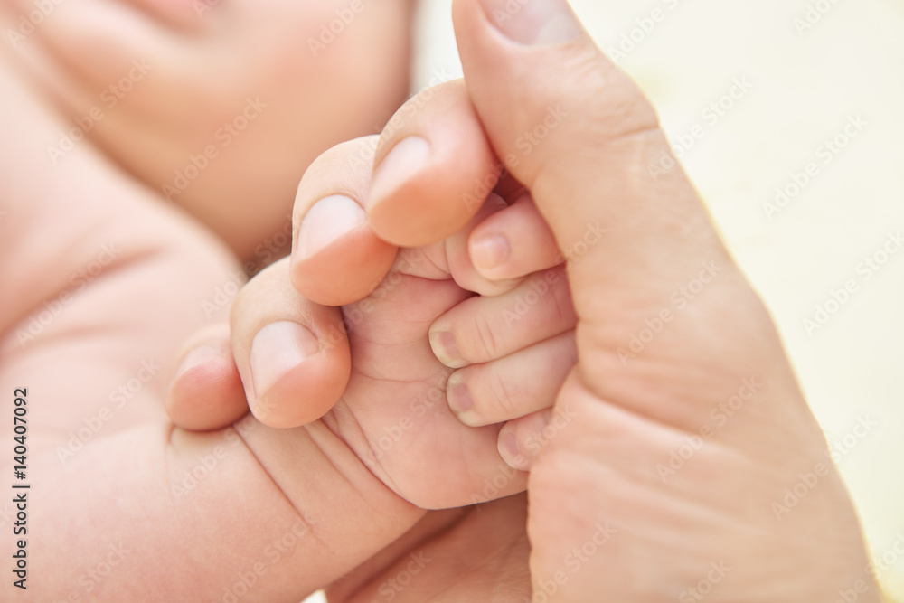 A parent holding the hand of a newborn baby A parent holding the hand of a newborn baby
