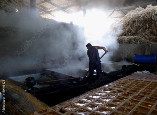 Man working hard in a hot steam filled shed, sugar refinery.