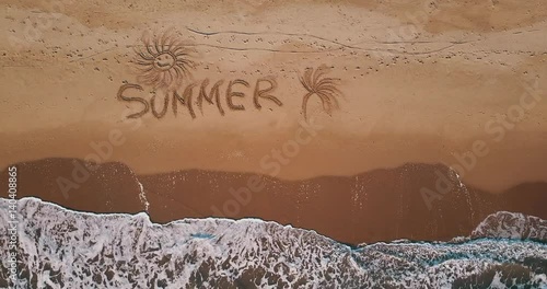 View from above, aerial view of some waves crashing on a beach where 'Summer' is written. photo