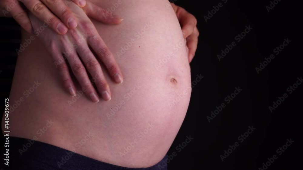 Couple with hands on naked belly of pregnant woman closeup on black background. Pregnancy, parenthood and baby anticipation concept. 4K ProRes HQ codec Couple with hands on naked belly of pregnant woman closeup on black background. Pregnancy, parenthood and baby anticipation concept. 4K ProRes HQ codec