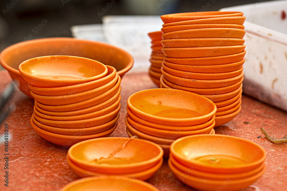 Orange bowls stacked on the street food stall Orange bowls stacked on the street food stall