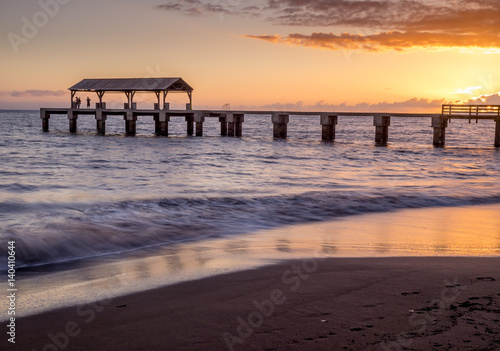 Photo of Waimea Town pier at sunset taken with long exposure used to smooth and blur the ocean.
