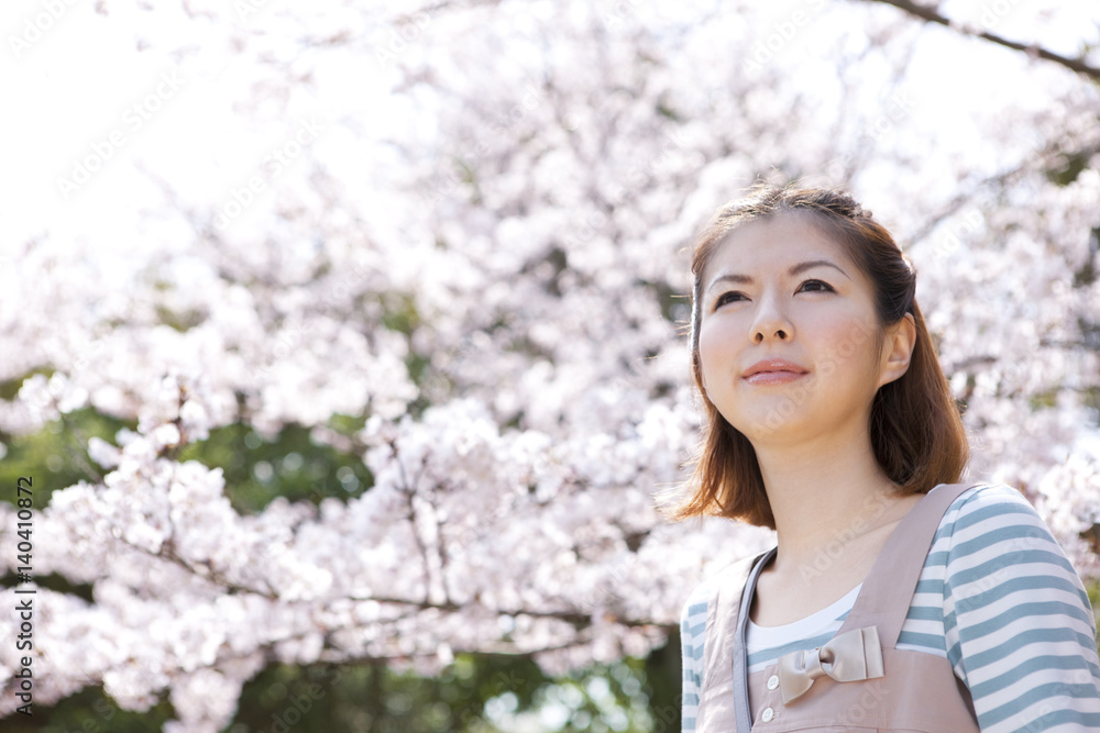 Young woman standing in front of cherry blossom tree Young woman standing in front of cherry blossom tree