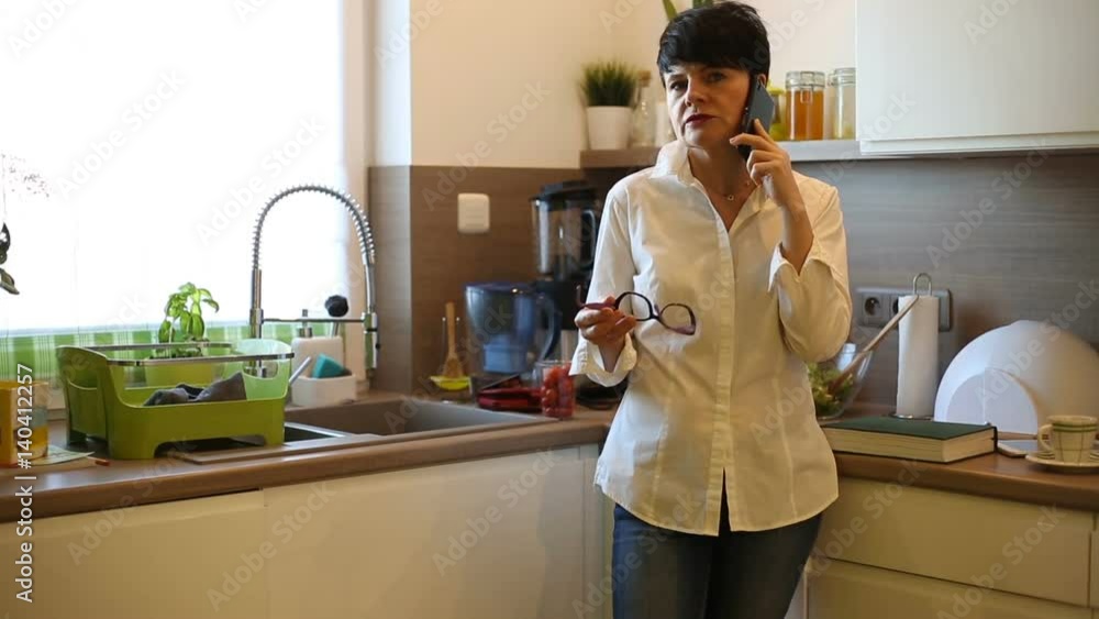 Elegant businesswoman standing in the kitchen and having a call
Elegant businesswoman standing in the kitchen and having a call