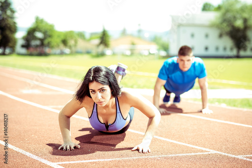 Young couple doing push ups on track.