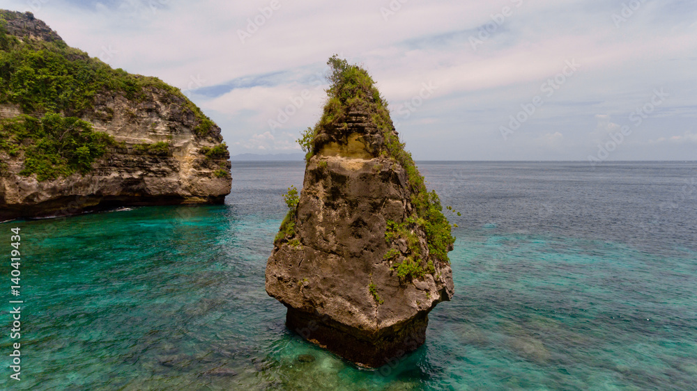 Aerial view of a cliff in the sea on the Suwehan beach. Nusa Penida, Indonesia. Aerial view of a cliff in the sea on the Suwehan beach. Nusa Penida, Indonesia.