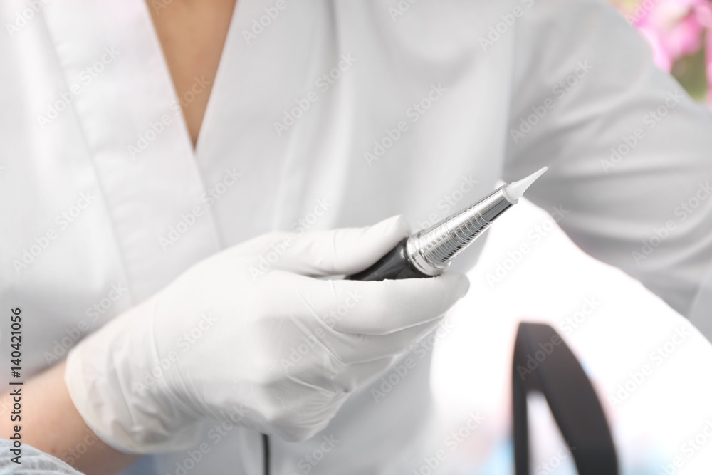 Specialist holding instrument for permanent makeup, closeup Specialist holding instrument for permanent makeup, closeup