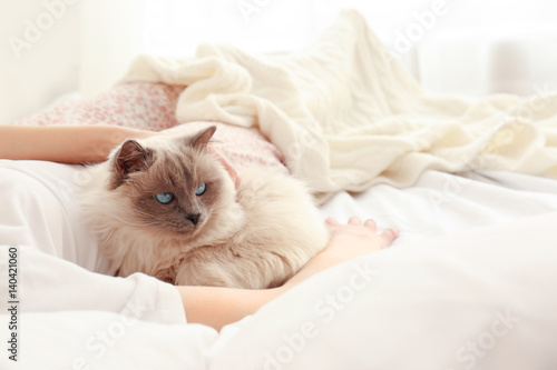 Young woman with cute cat lying on bed at home