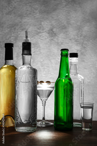 Different bottles of wine and spirits on color background