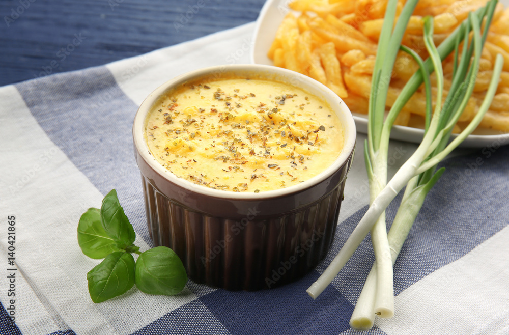 Bowl with cheese sauce, green onion and napkin on wooden table Bowl with cheese sauce, green onion and napkin on wooden table