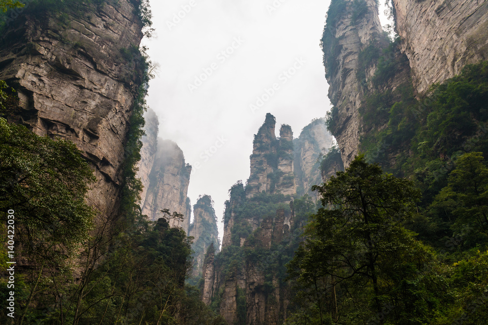 mountains are surrounded by clouds at Zhangjiajie, a national park in China known for its surreal scenery of rock formations.