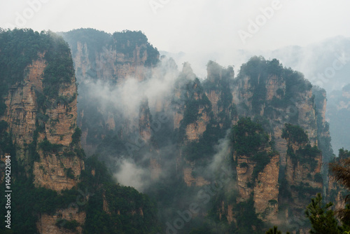 mountains are surrounded by clouds at Zhangjiajie, a national park in China known for its surreal scenery of rock formations.