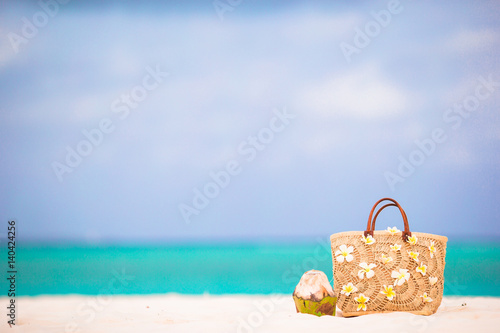 Closeup beautiful bag with frangipani flowers and coconut on white beach