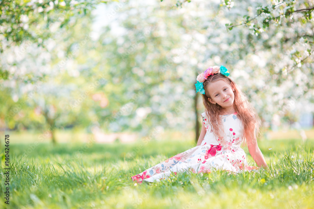 Adorable little girl in blooming cherry tree garden on spring day Adorable little girl in blooming cherry tree garden on spring day