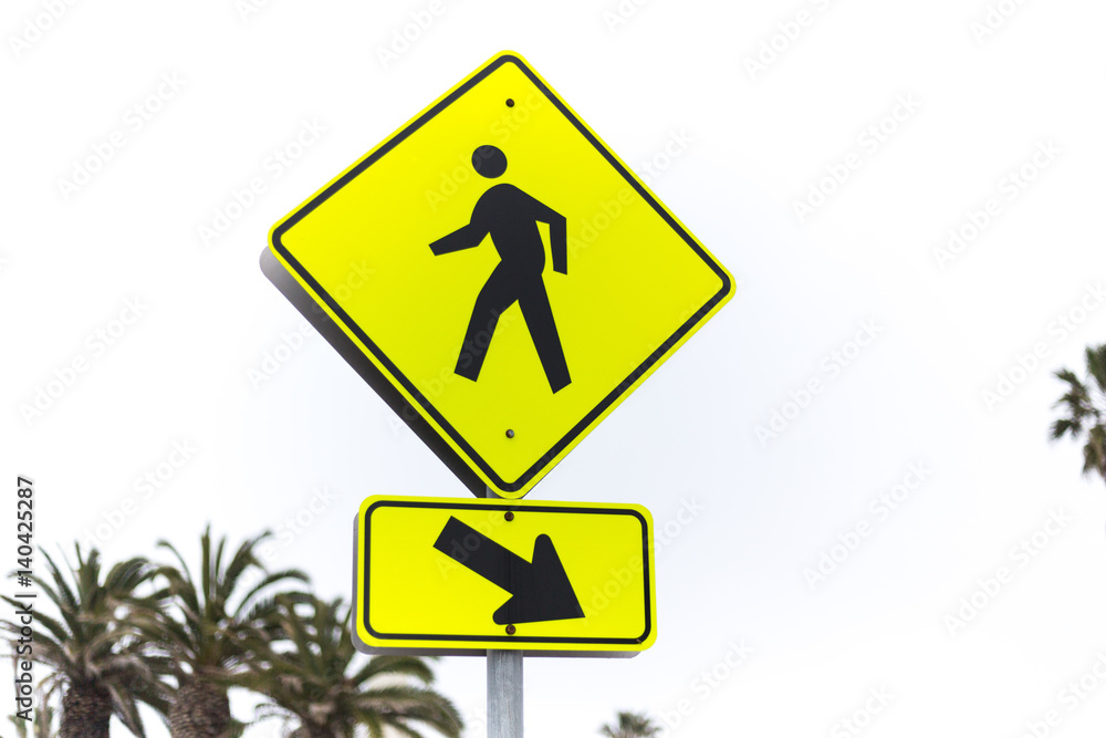 Yellow road sign pedestrian crossing and palm tree Yellow road sign pedestrian crossing and palm tree
