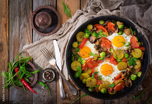 Breakfast for two. Fried eggs with vegetables - shakshuka in a frying pan on a wooden background in rustic style. Flat lay. Top view photo