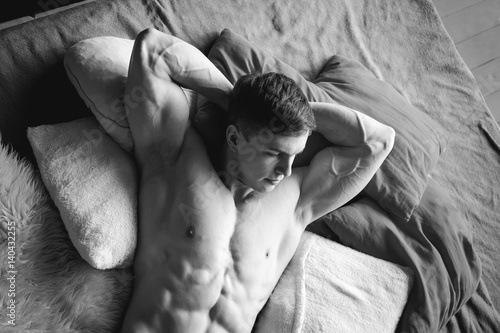 Fotografía studio portrait young sexy men bodybuilder athlete, with a bare torso, lies on a